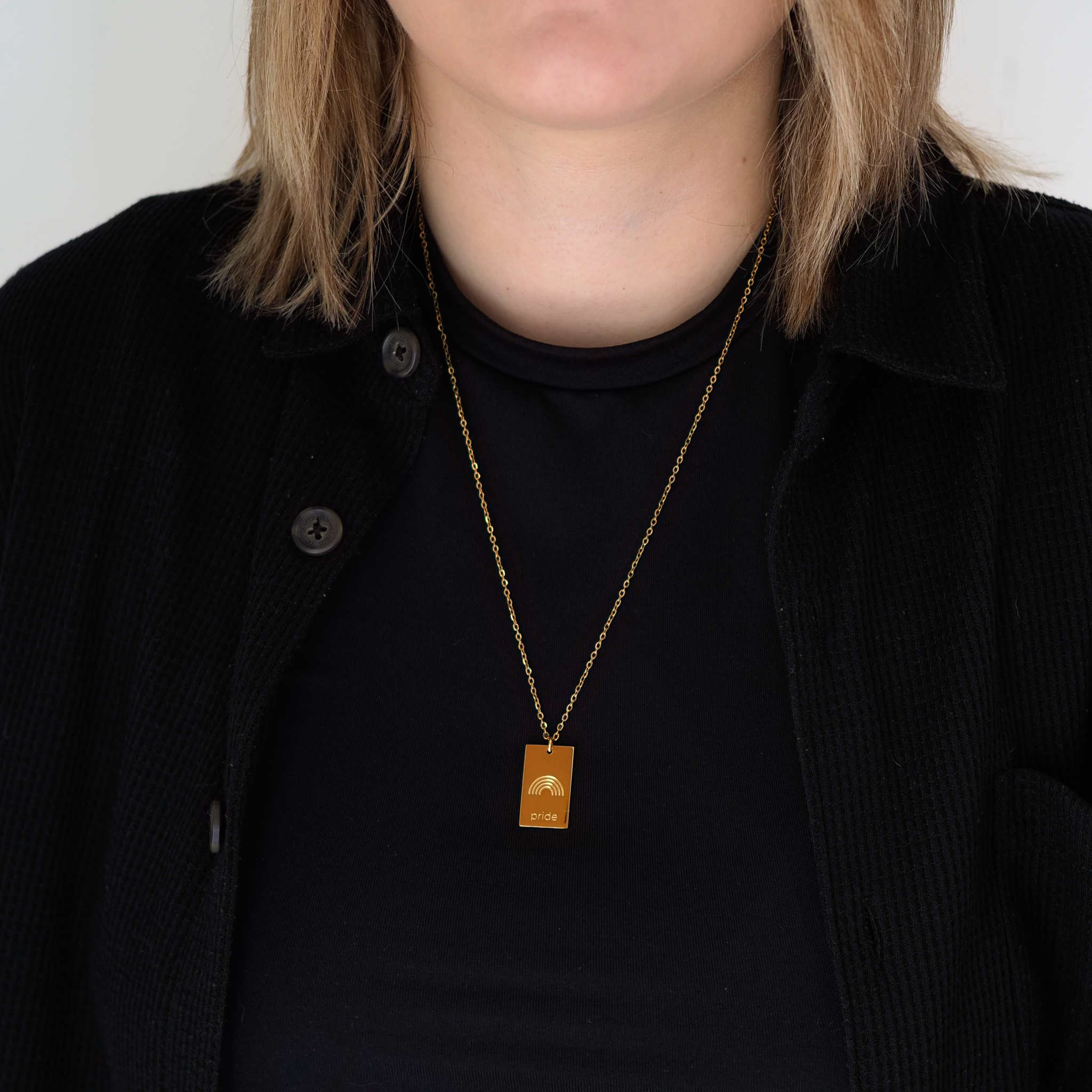 pride tag necklace with rainbow symbol and pride text in pride jewellery collection, model gold